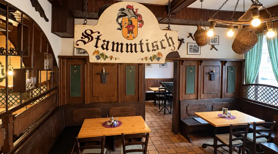 Der Stammtisch mit dem geschnitzten Wappenschild, davor gedeckte Tische und Bänke