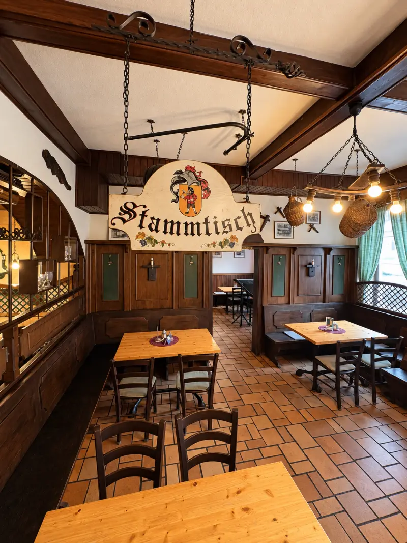 Gaststube mit dem Stammtischschild und dem Hauswappen unter der Holzdecke