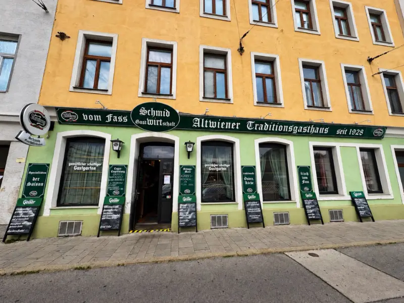 Fassade der Gastwirtschaft Schmid mit dem grünen Schild „Schmid Gastwirtschaft — Altwiener Traditionsgasthaus seit 1928“, davor Tafeln mit den Tagesempfehlungen